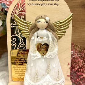 Pamiątka Komunii: anioł z białej koronki, złotych skrzydeł, haftu, na drewnianej podstawie z grawerem.