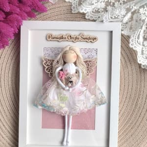 Ramka pamiątkowa z aniołkiem tekstylnym, pastelowa, zdobiona koronką, wykonana z drewna i tekstyliów.